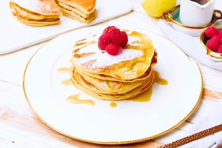 A stack of pancakes with fresh raspberries 