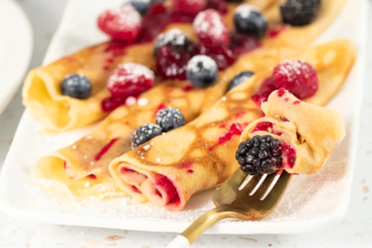 Crepe-like pancakes on a plate with fresh berries