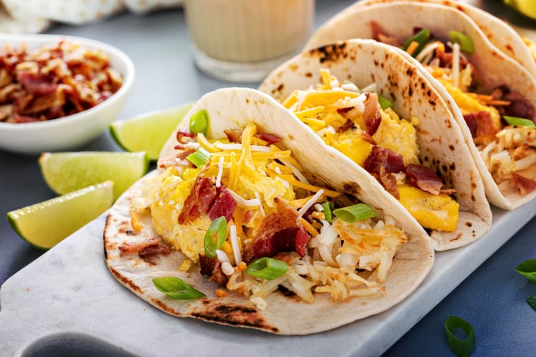 Three breakfast tacos filled with egg, cheese and bacon
