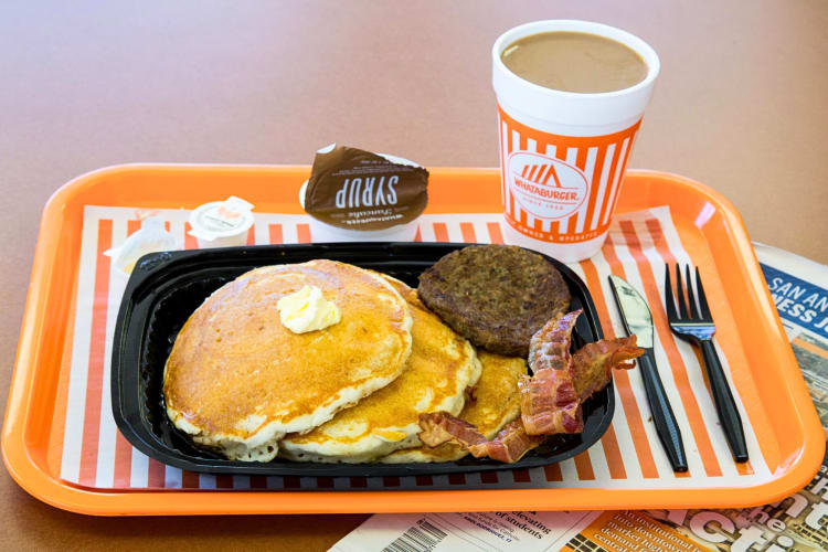 Pancakes with a patty and bacon, next to a coffee, from the Whataburger breakfast menu