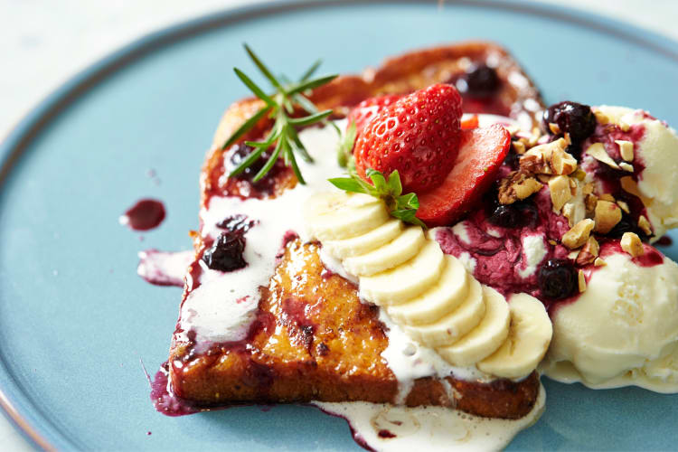 French toast with banana, strawberries, blueberries, nuts and whipped cream on top