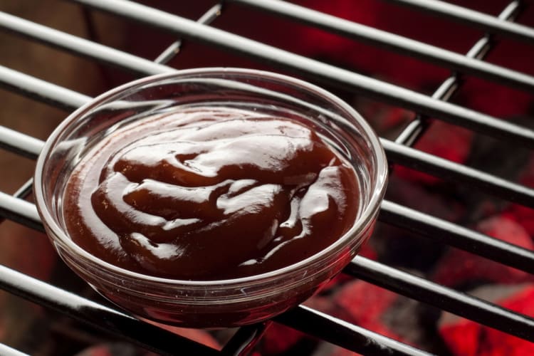 A small bowl of barbecue sauce on a grill