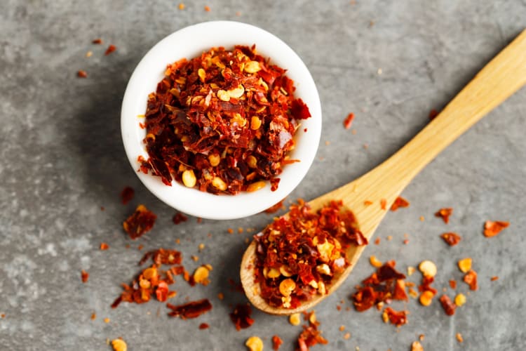 A bowl and a spoon with dried red pepper flakes