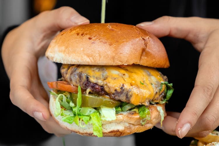 Two hands holding a burger, from Parc, a birthday restaurant in Detroit