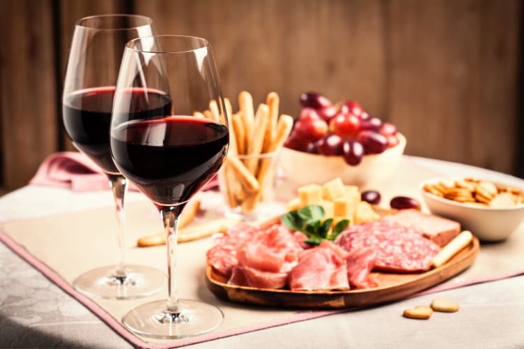 Two glasses of red wine next to a charcuterie board