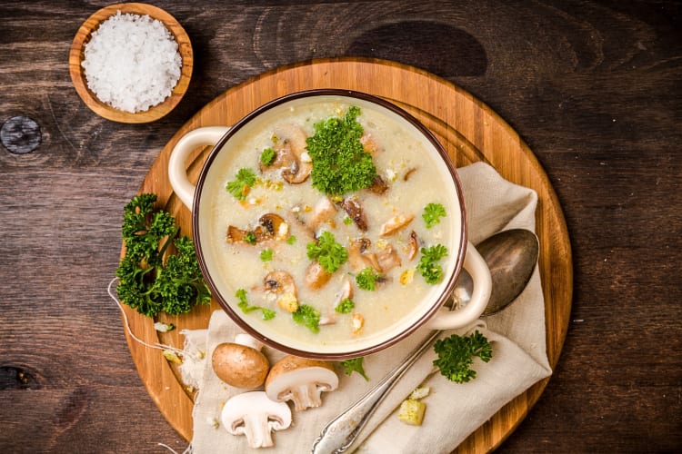 Aerial view of mushroom soup with parsley, mushroom slices and salt