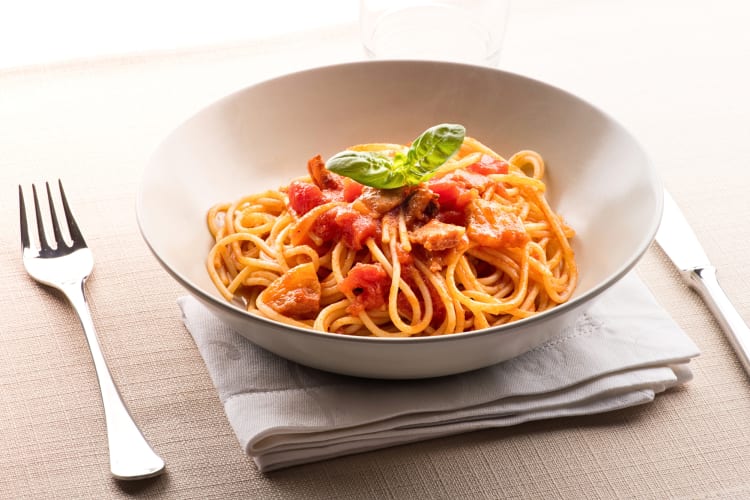 Pasta Amatriciana in a bowl in between a knife and fork