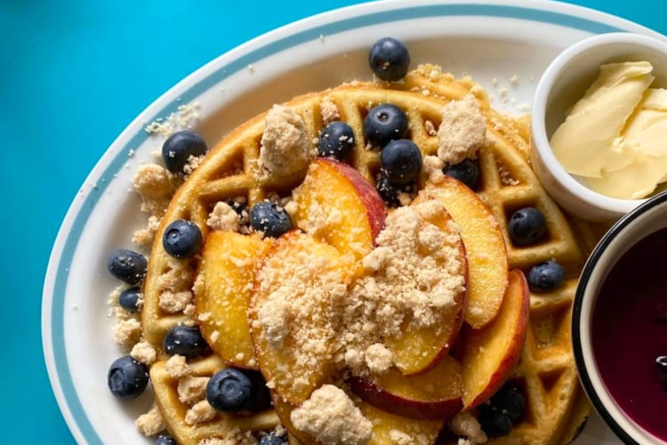 Waffles with peaches, blueberries, compote and butter