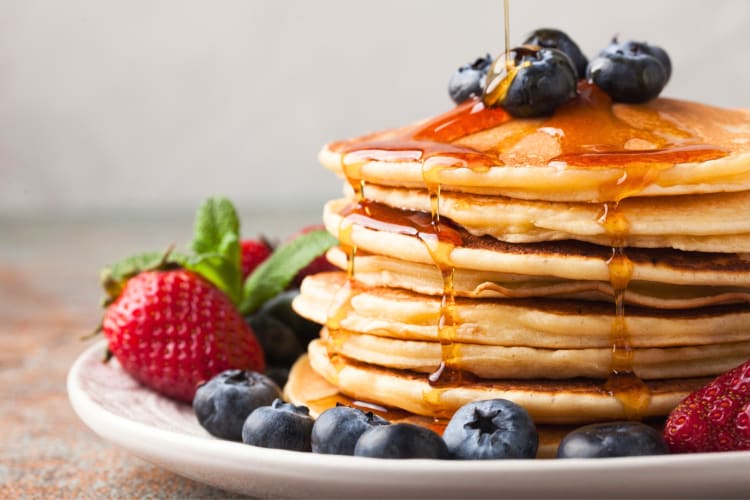 A stack of pancakes with syrup and berries