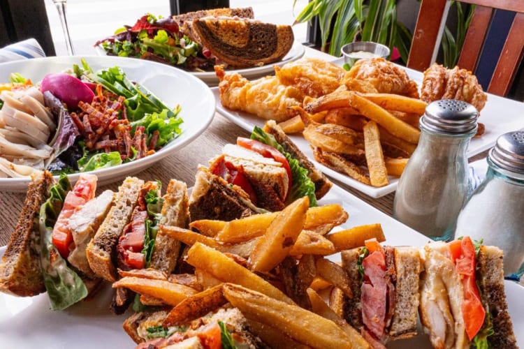 Sandwiches with fries and salads on a table
