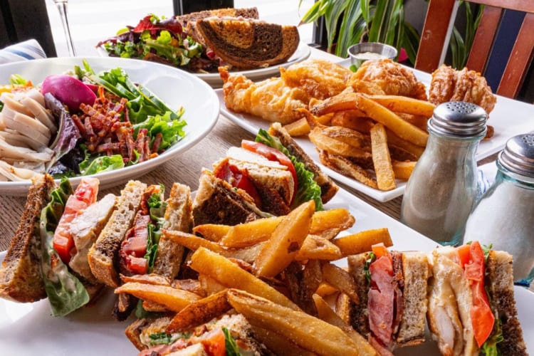 Sandwiches with fries and salads on a table