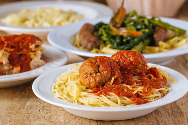 Spaghetti and meatballs on a table next to other dishes