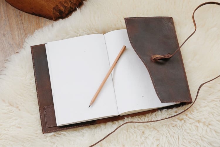 A leather-bound journal on a sheepskin rug