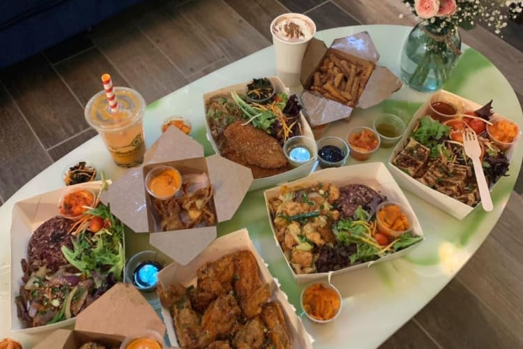 A table full of delicious takeaway Korean-style food and drinks.