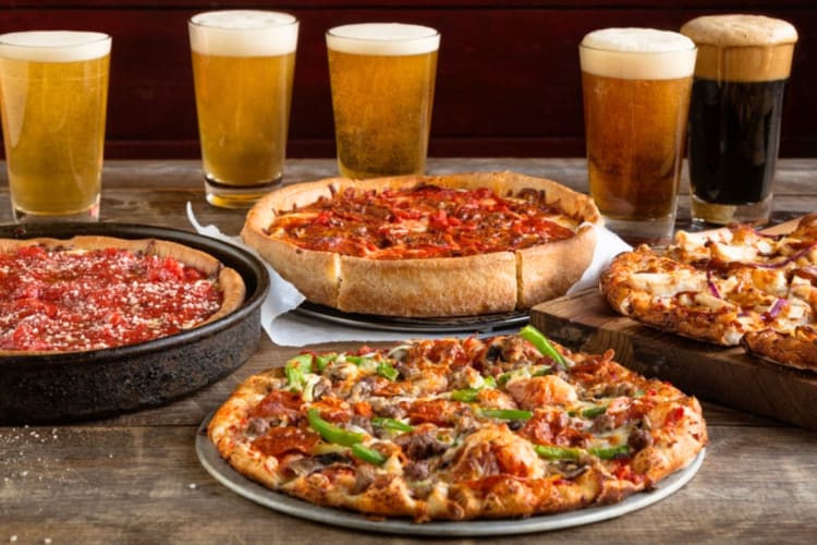 Four pizzas and pints of beer on a table