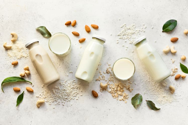 Bottles of plant based milk and many kinds of nuts