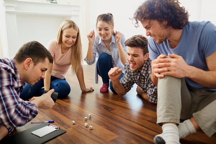 Five friends watching dice being rolled while playing a game