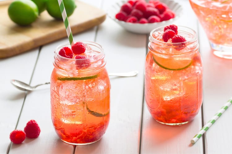 Glass jars of raspberry iced tea next to ingredients