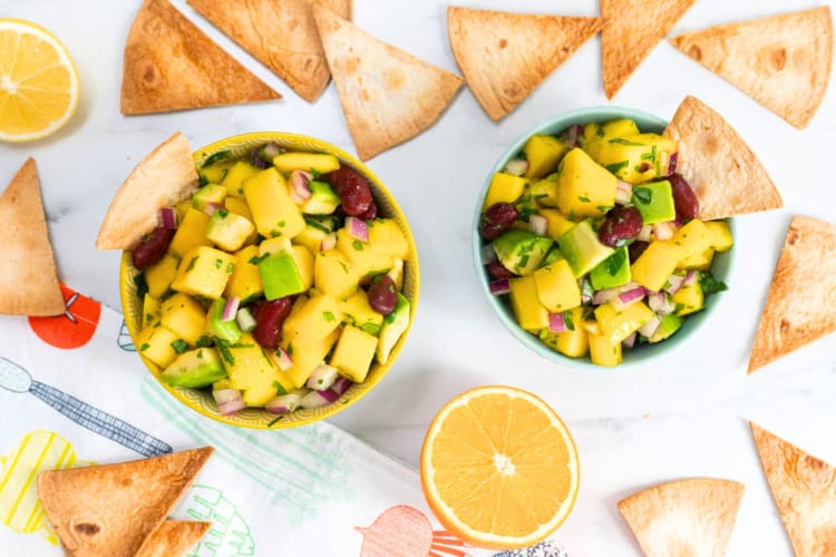 A bowl of mango and avocado salsa surrounded by tortilla chips