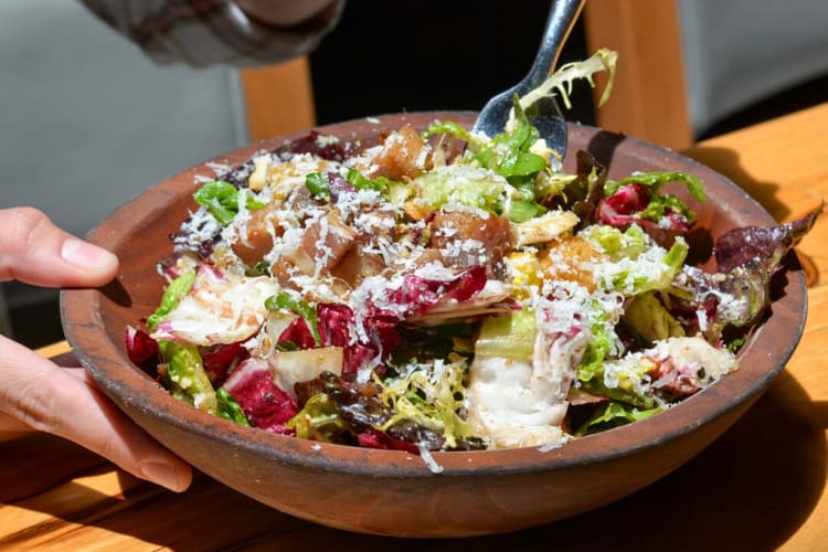 Close-up of hands eating a salad from Prato, a restaurant in Orlando