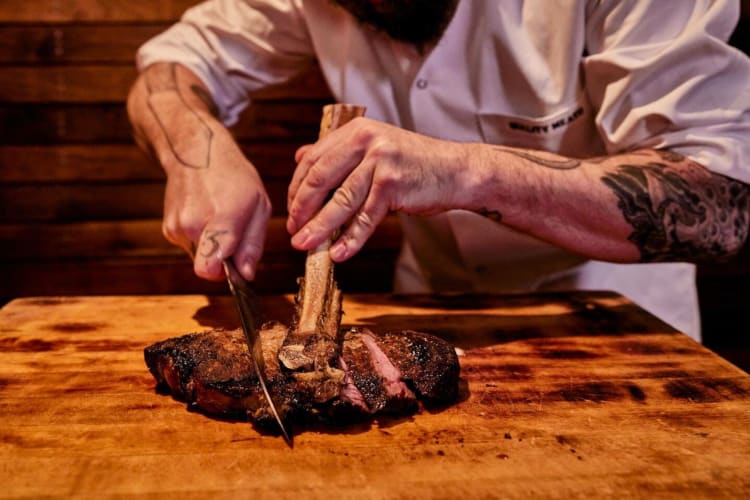 Chef from the restaurant Quality Meats cutting up a steak