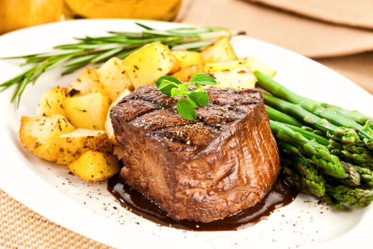 Filet Mignon with a side of asparagus and potatoes served at the best steakhouses in NYC