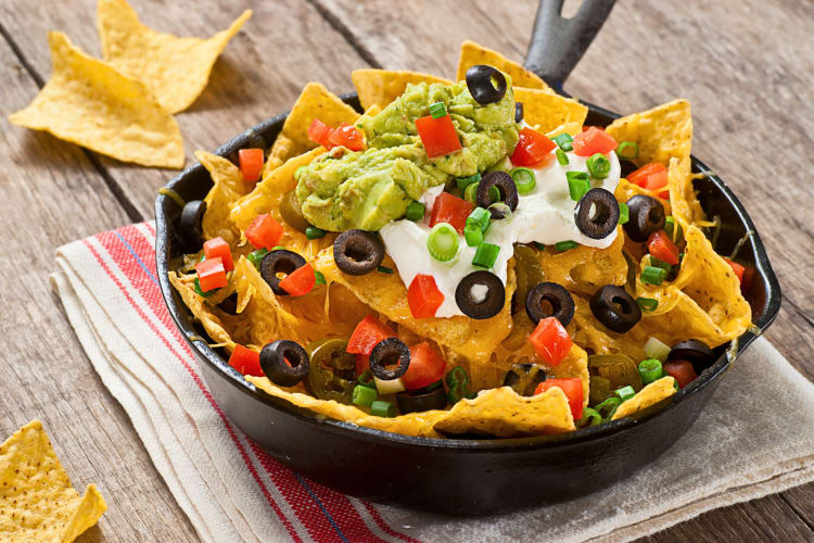 Nachos with guacamole, sliced olives and tomatoes