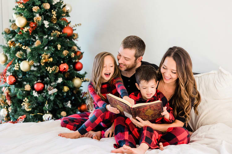 A family of four reading a book together as a family Christmas tradition