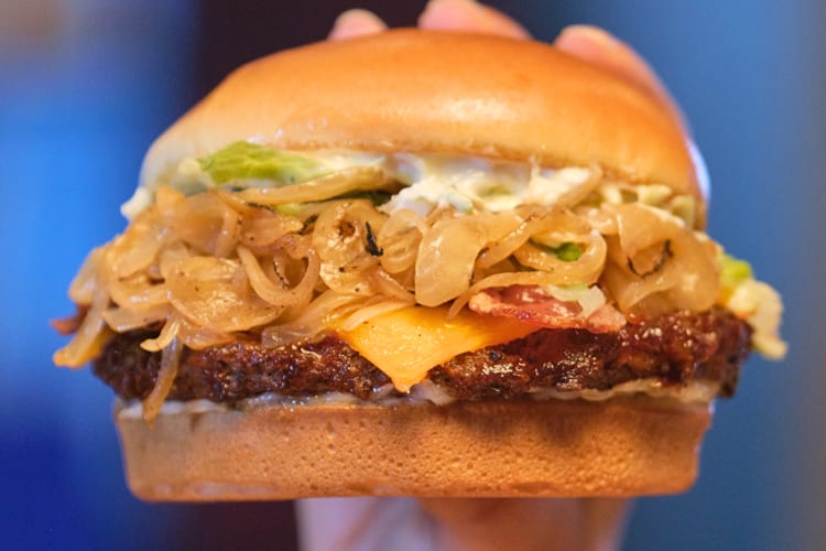 Close-up pf a person's hand holding a burger from Red Robin