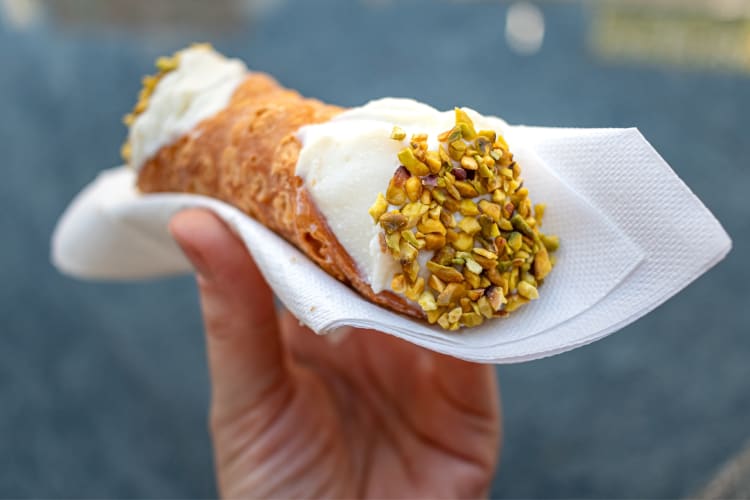 A person holding a cannoli