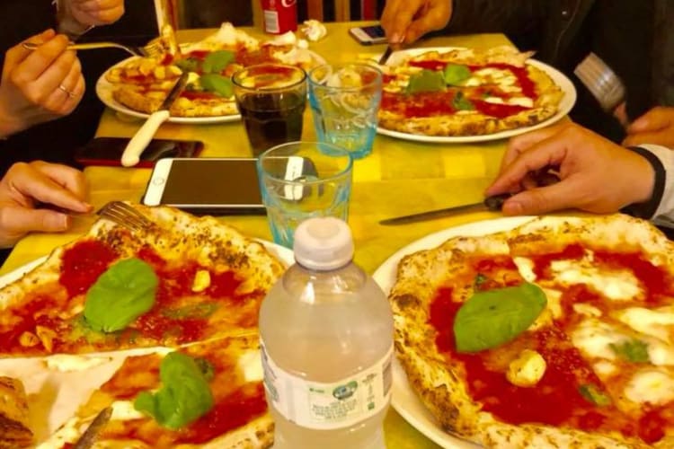 People eating pizza in a restaurant in Milan.