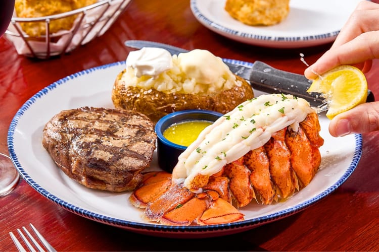 A meal with steak, lobster and a baked potato
