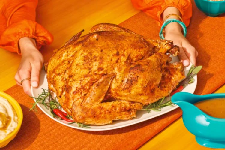 A person holding a cooked turkey 