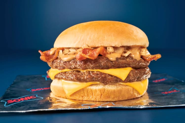 A burger with bacon, cripsy onions, sauce and cheese