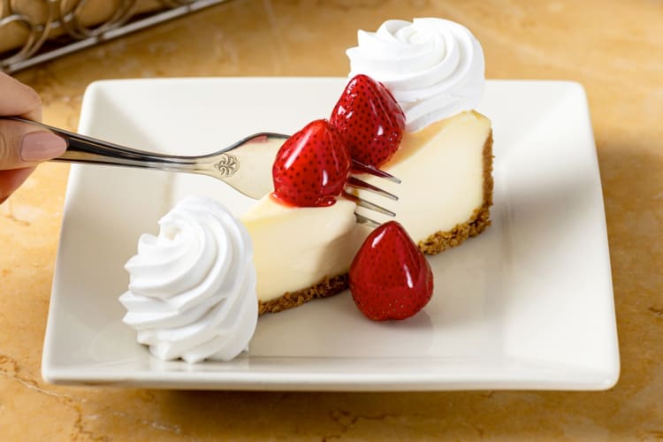 A slice of cheesecake with glazed strawberries