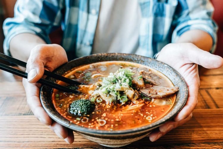 Someone holding a bowl of beef noodle soup