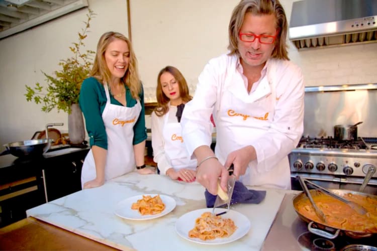 Three people making a pasta dish in a cooking class