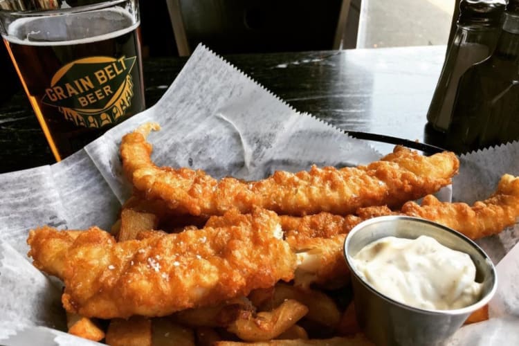 Fish and chips next to a pint of beer in a Grain Belt Beer glass