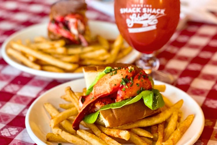 A lobster roll and fries next to a cocktail