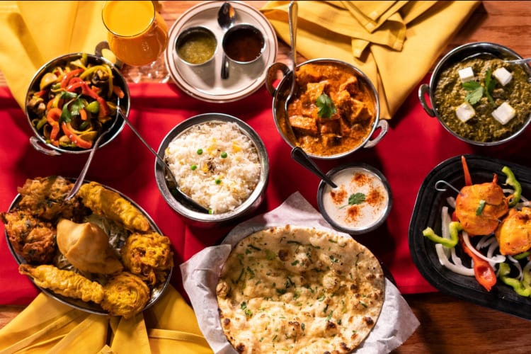 Indian food dishes on a table with red and yellow cloths