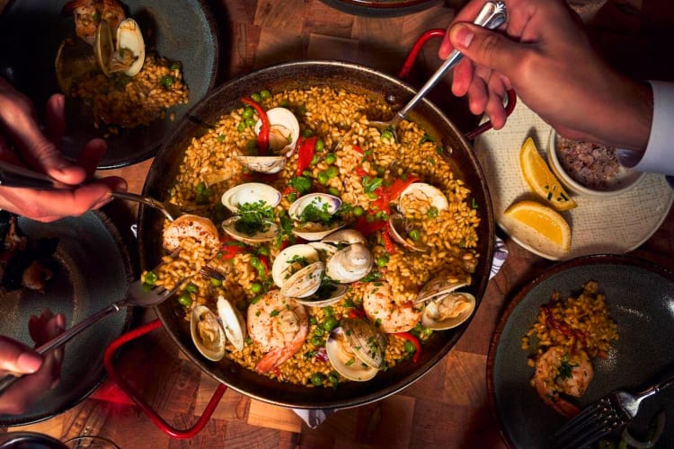 A group of people serving themselves to seafood paella