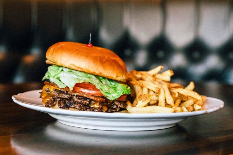 A burger and fries on a plate on a dark wood table