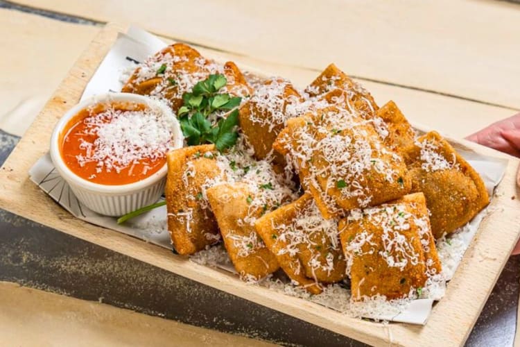 A plate of toasted ravioli with cheese and marinara