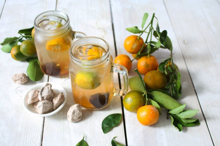 Calamansi juice in two different glasses, surrounded by calamansi fruit