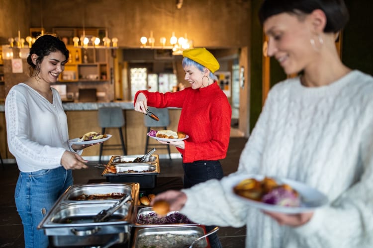 three women choosing food at buffet brunch