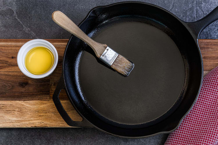 brushing oil onto cast iron skillet