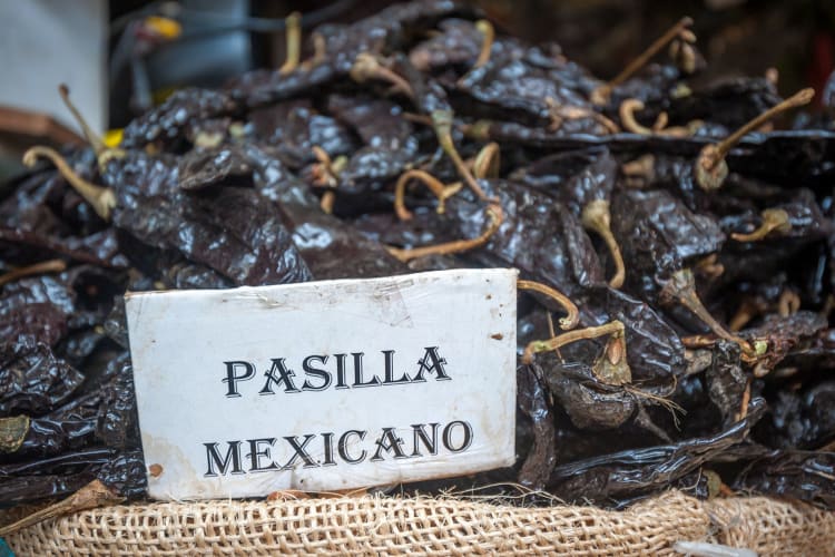 pasilla peppers grouped on a burlap surface with Pasilla Mexicano name card