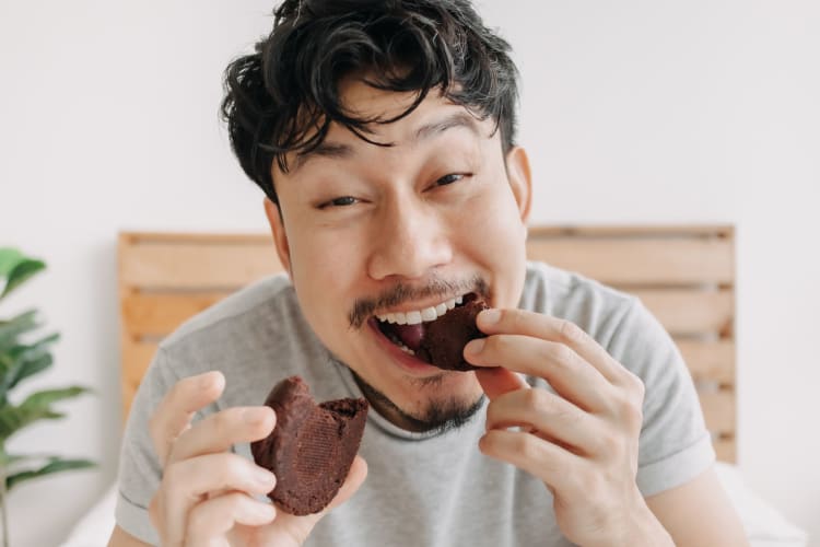 a young man happily eating a cookie