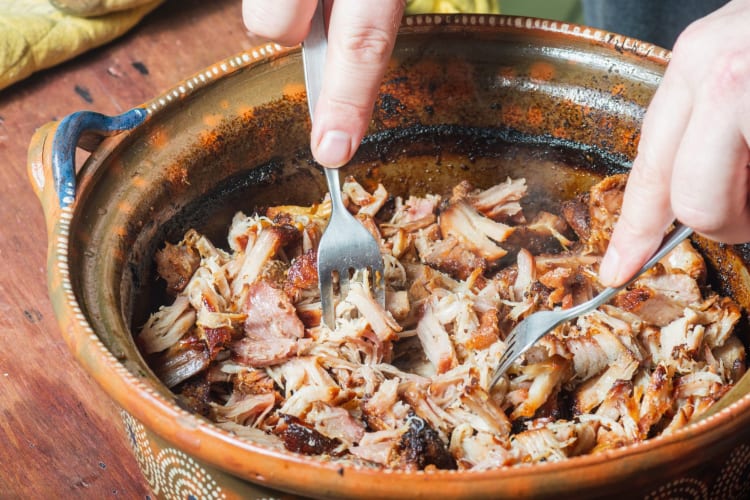 shredding carnitas in the cooking vessel