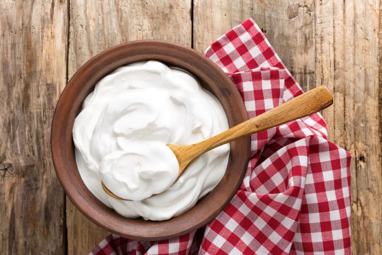 A wooden spoon in a bowl of yogurt, which works well as a cream of tartar substitute